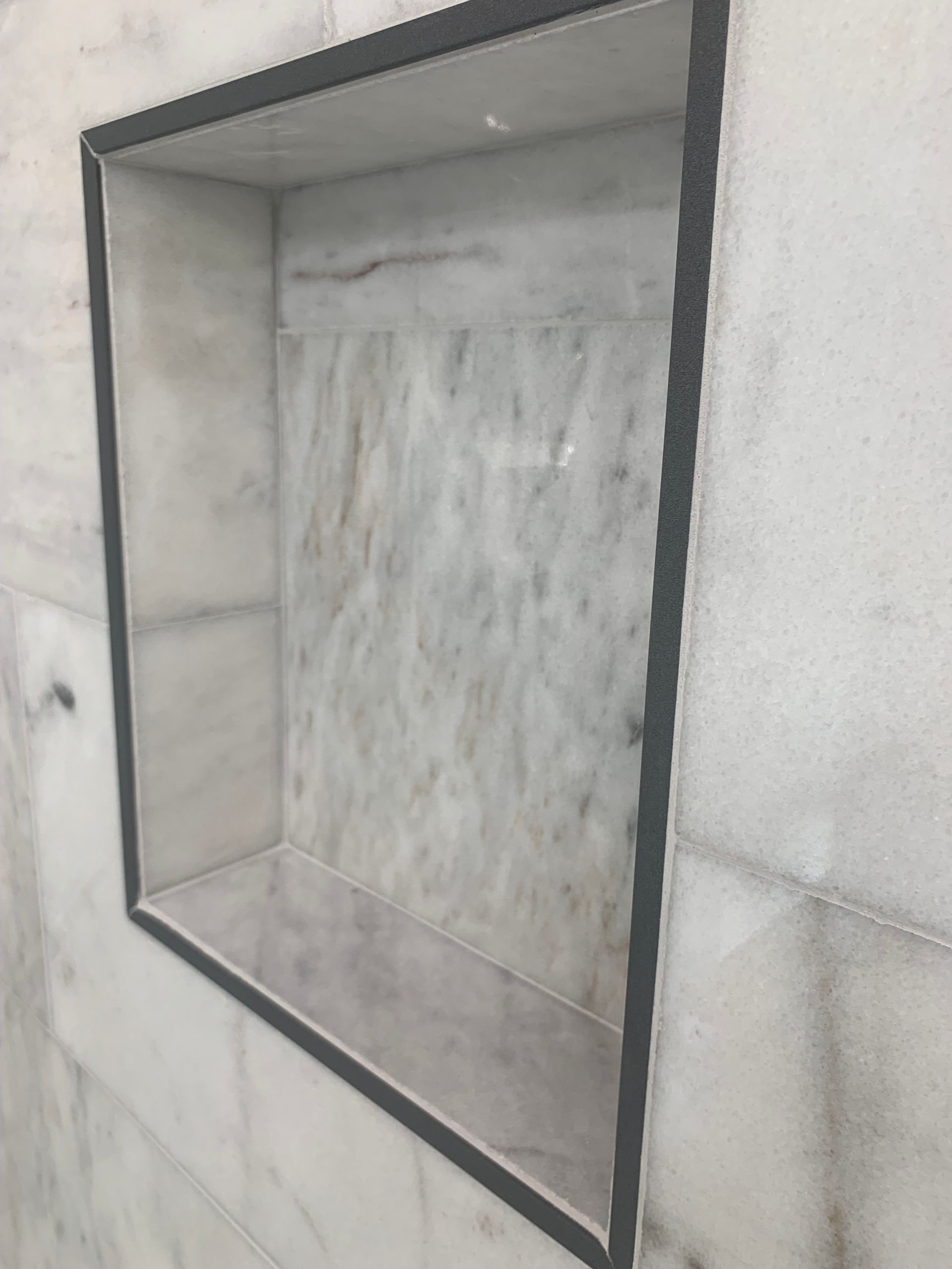 Built-in marble-lined wall niche with a dark metal frame