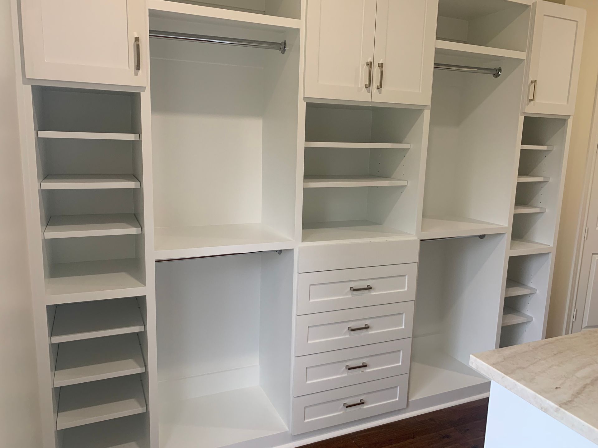 Built-in white walk-in closet with shelves, hanging rods, drawers, and cubbies