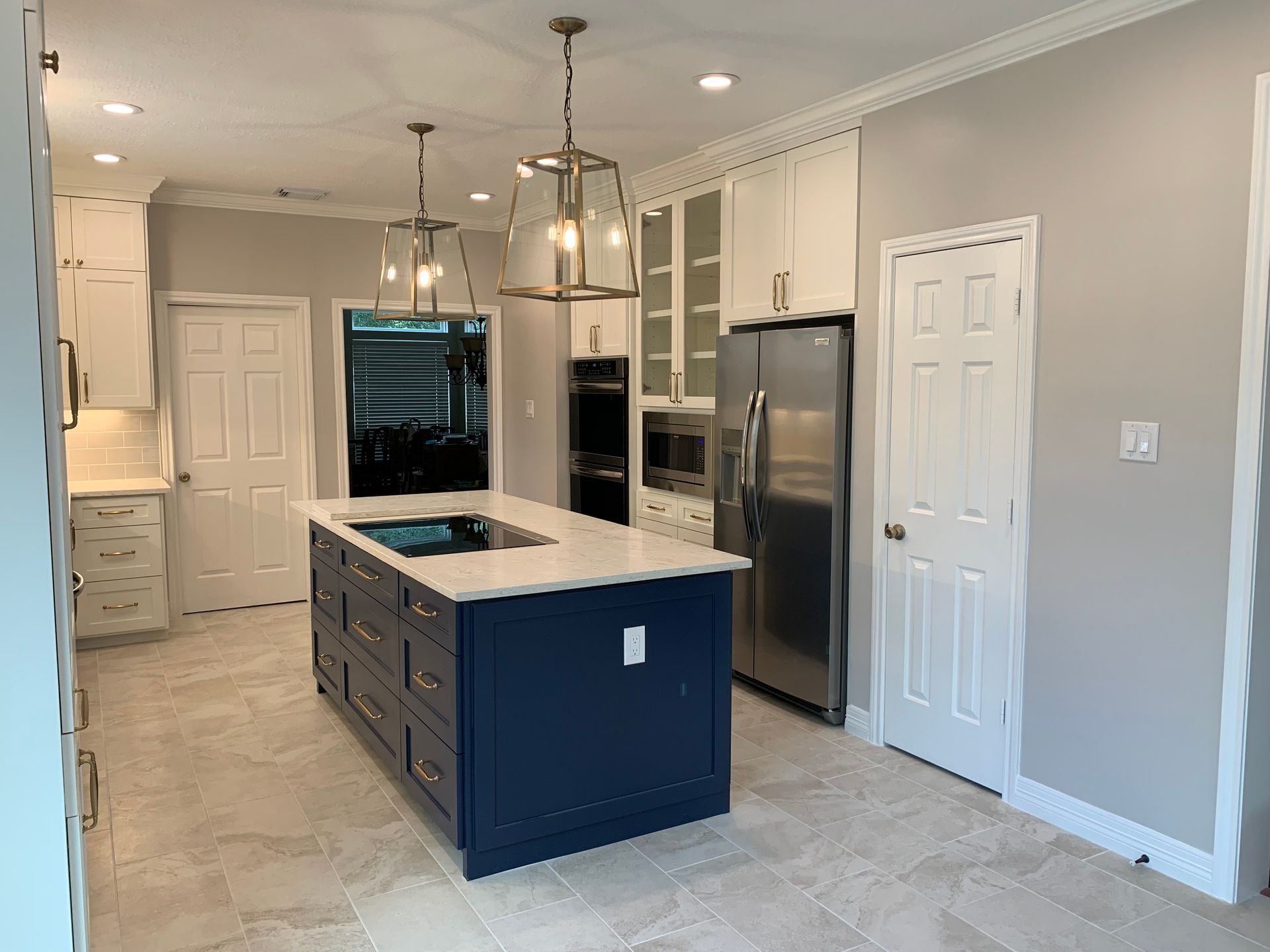 Modern kitchen with navy island, white countertops, stainless fridge, and light gray walls