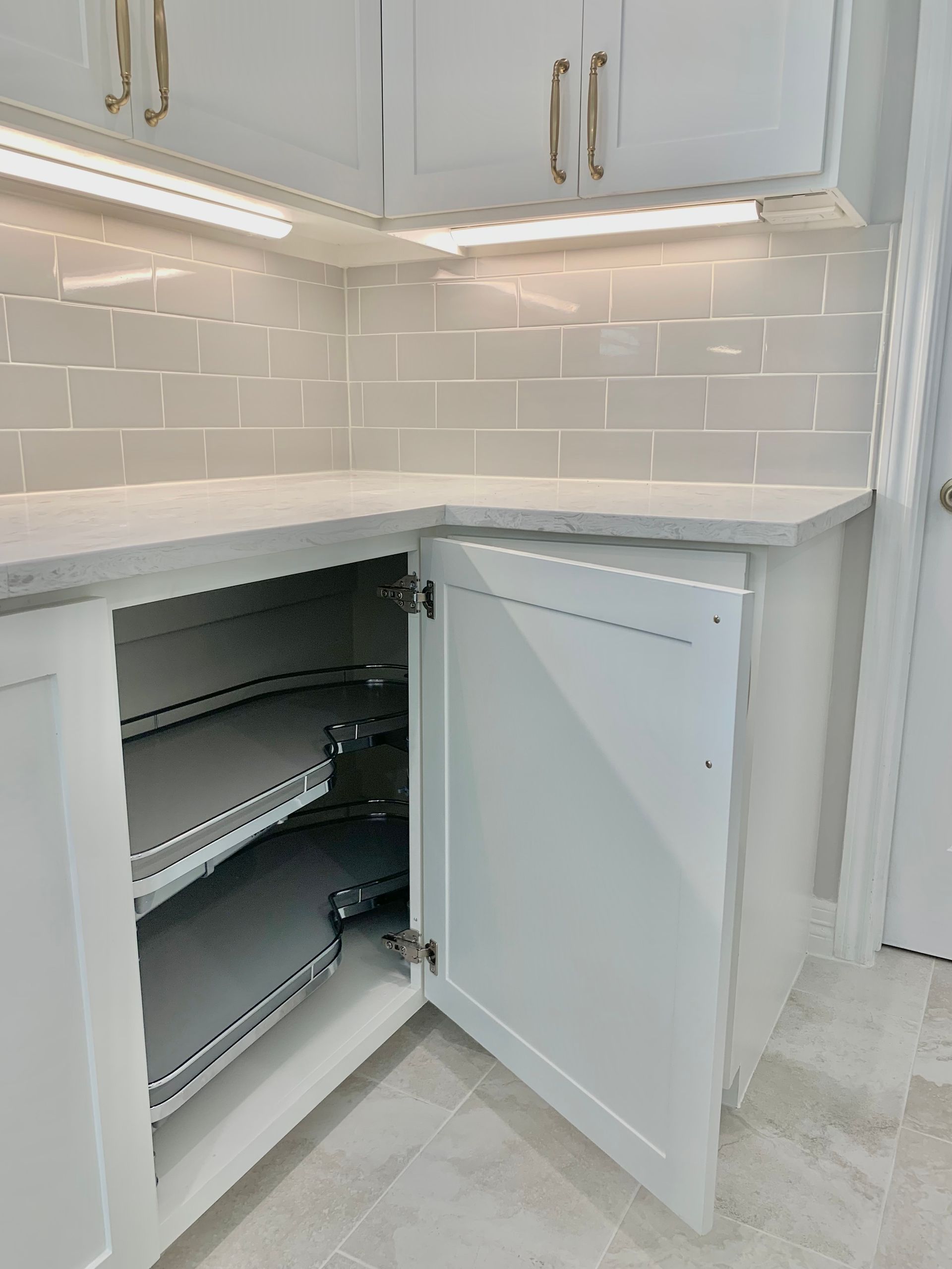 White kitchen cabinets with an open lower pantry revealing pull-out shelves and storage drawers.