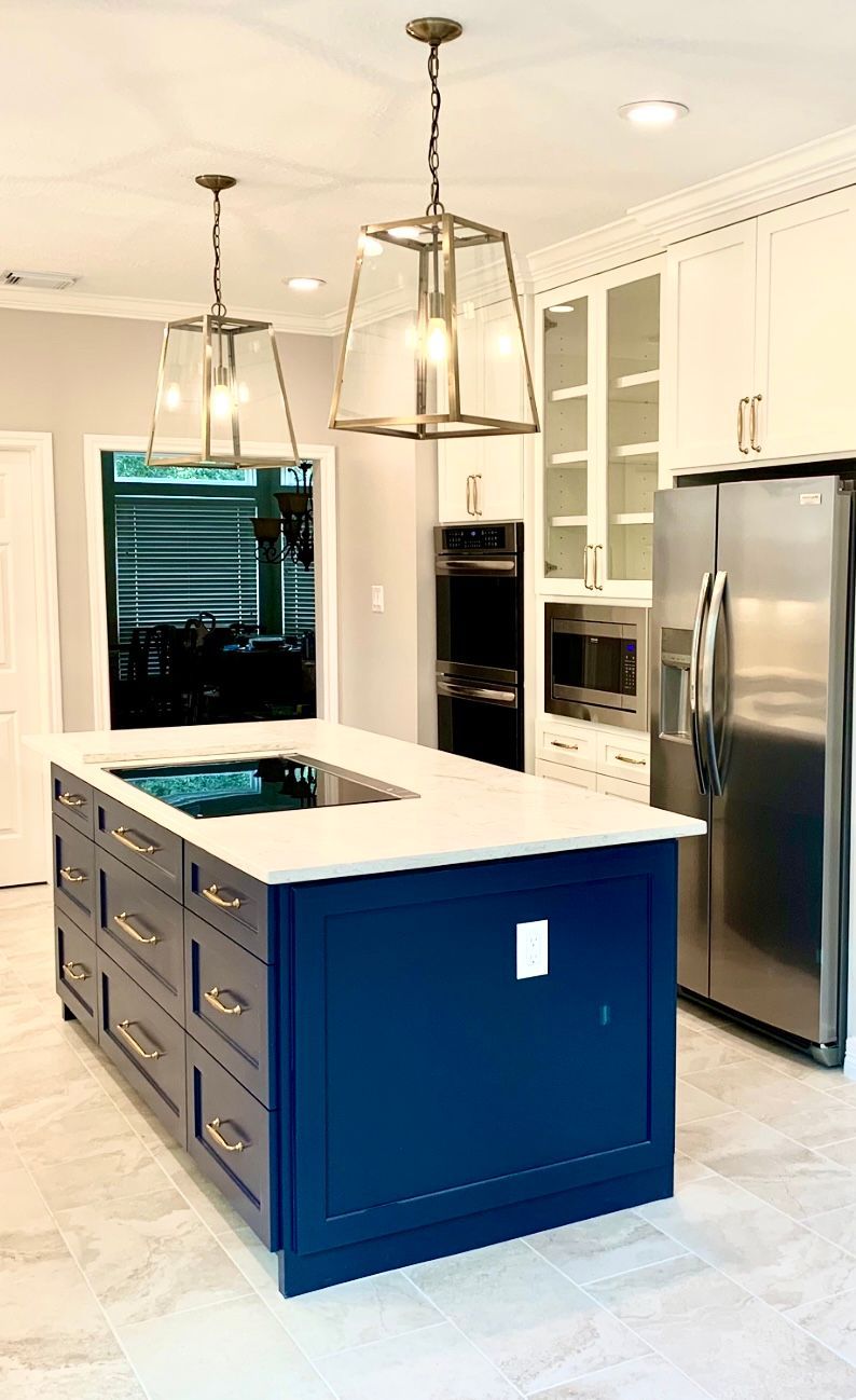 Modern kitchen with blue island, white cabinets, stainless steel appliances, and pendant lights