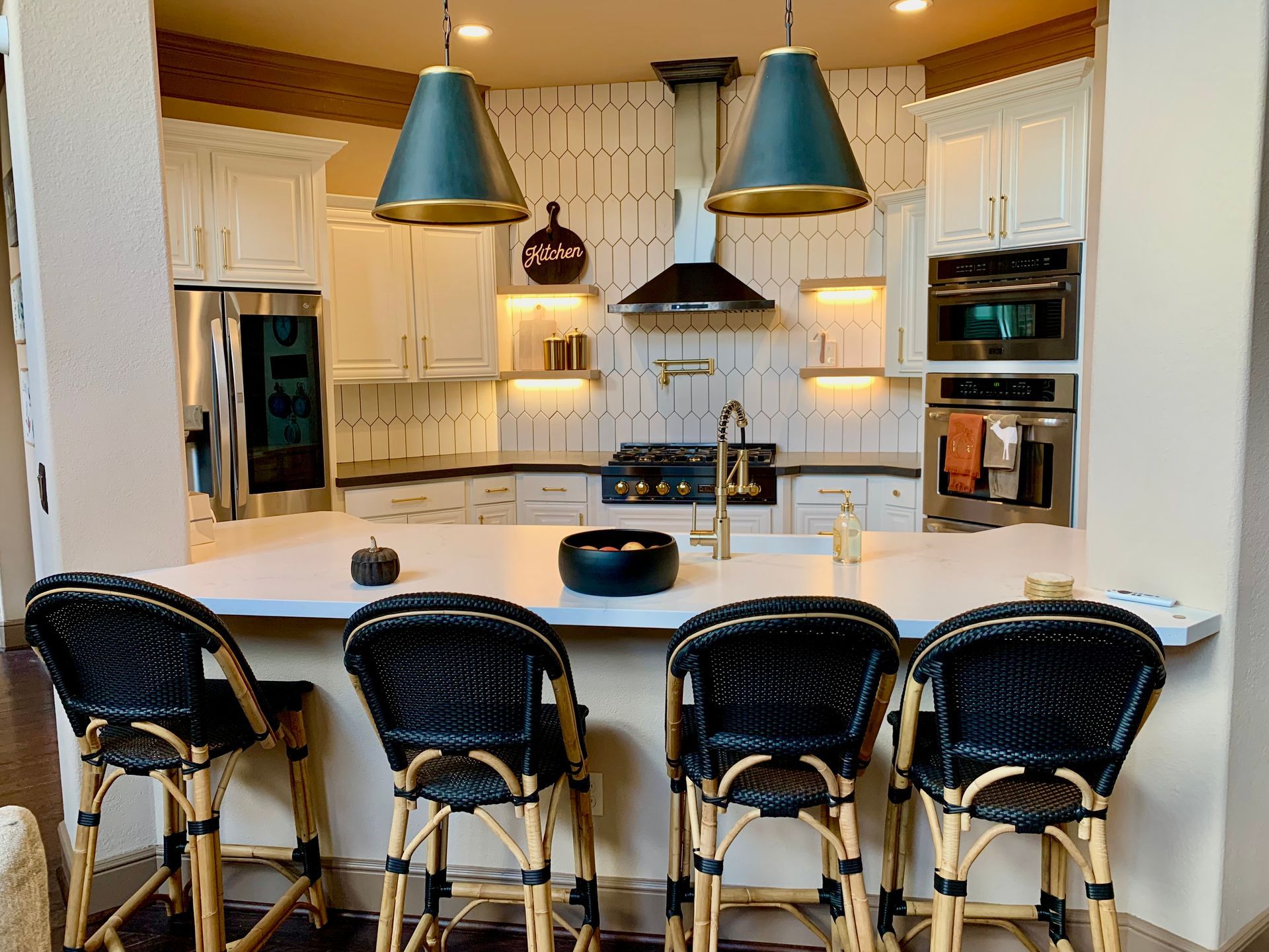 Bright kitchen with white cabinets, island bar stools, and blue pendant lights