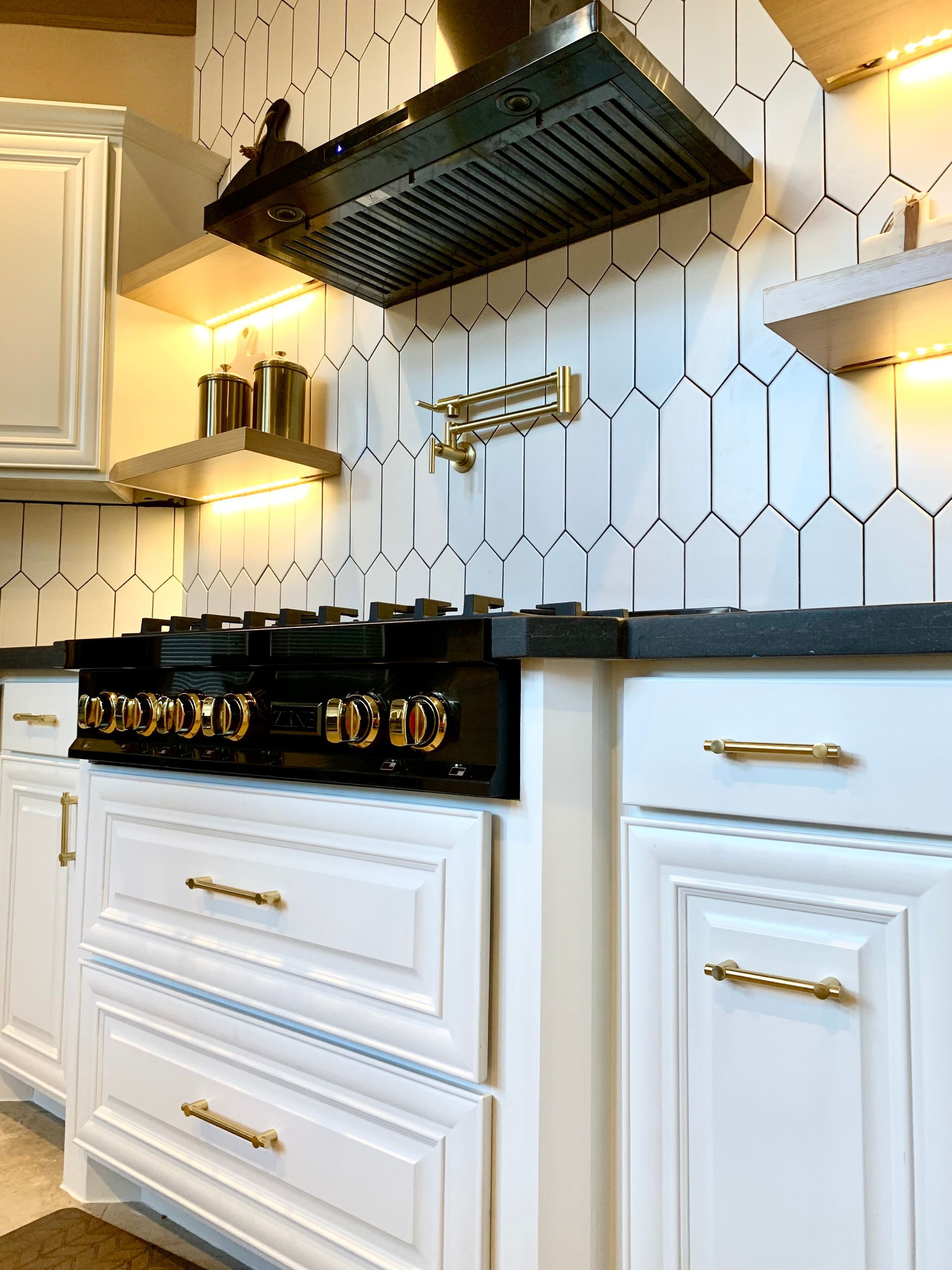 Modern white kitchen with black range hood, hex tile backsplash, and black stove on white cabinets
