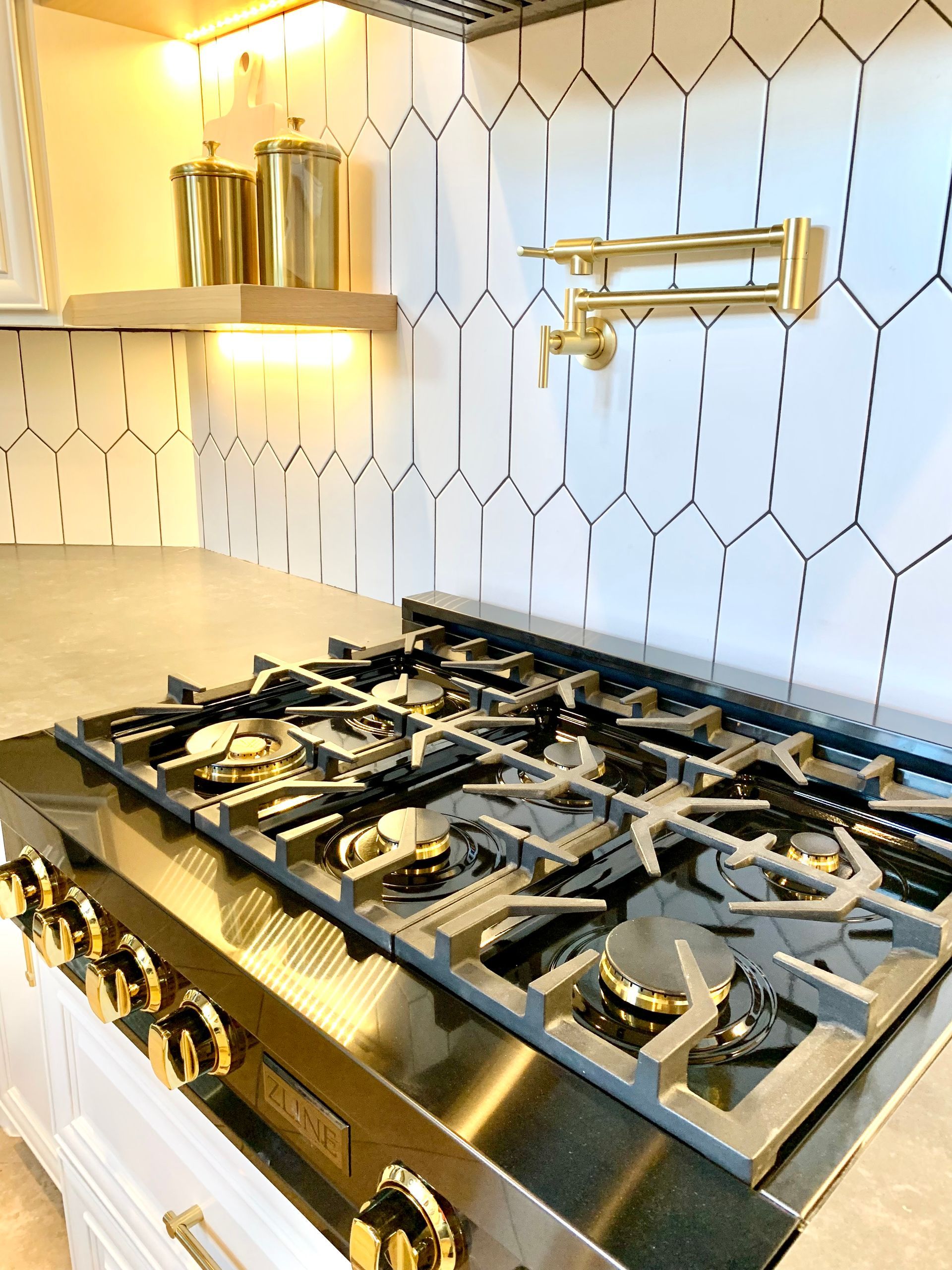Modern kitchen with a stainless steel gas range and white patterned tile backsplash