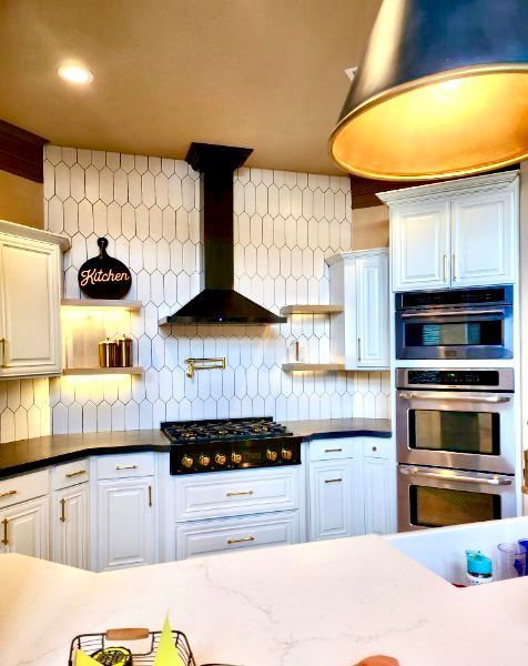 Bright white kitchen with black range hood, double ovens, and large island countertop