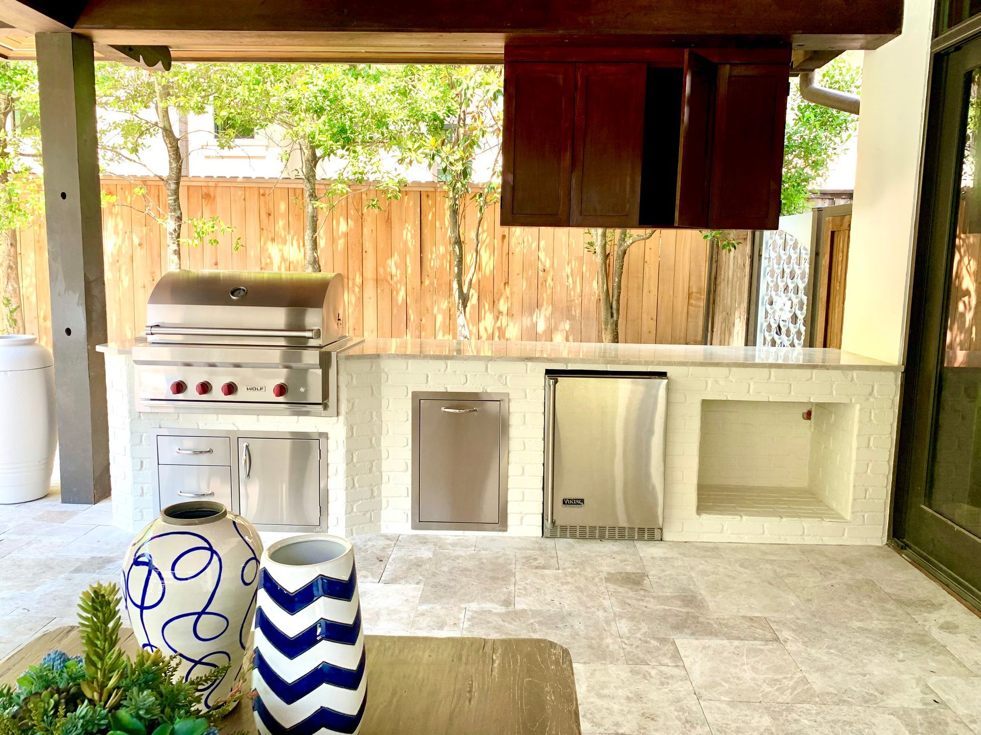 Outdoor backyard kitchen with a stove, sink, cabinet, and blue-and-white decorative jars