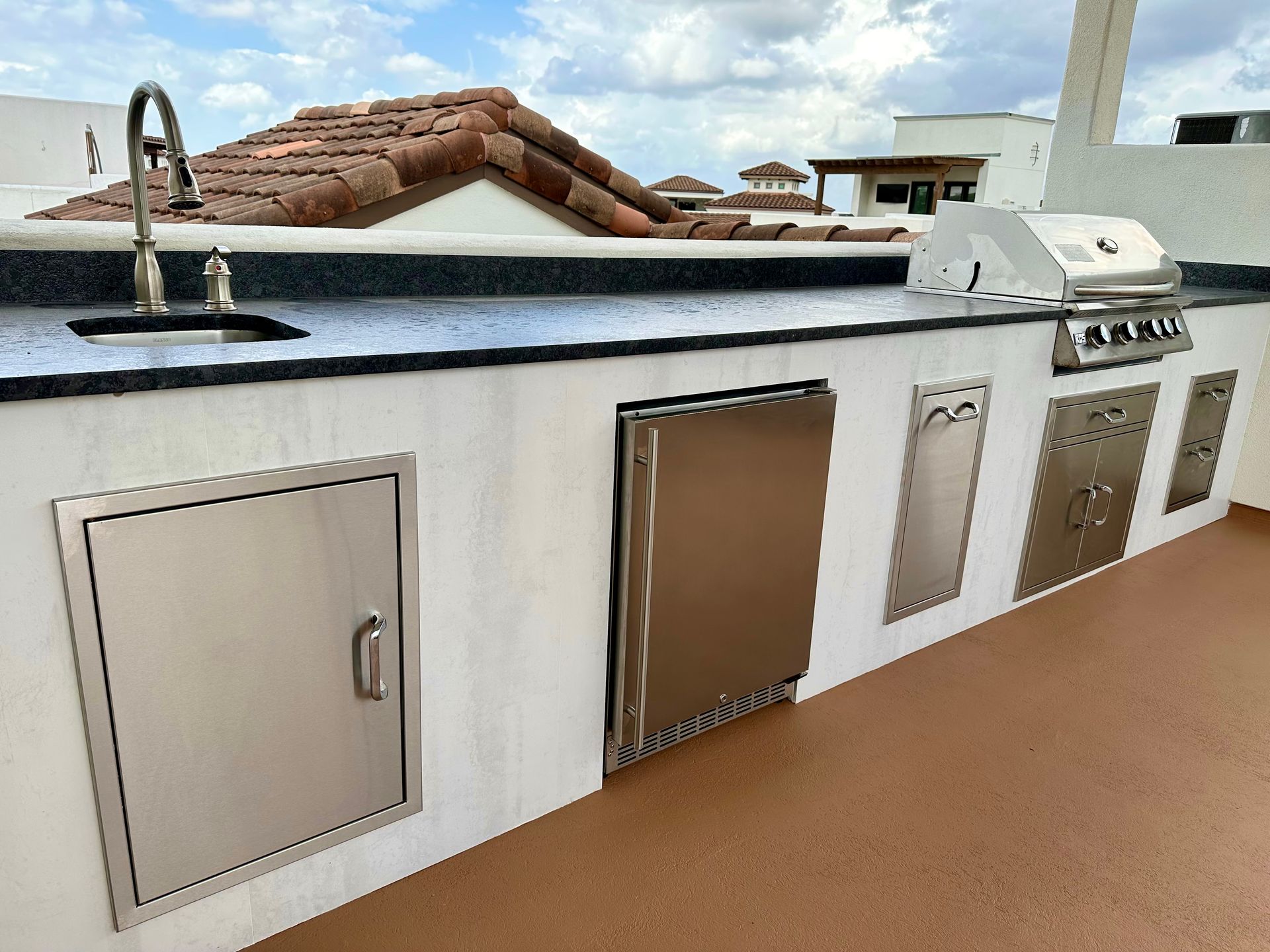 Rooftop utility area with metal access doors, sink faucet, and brown flooring against a white wall.