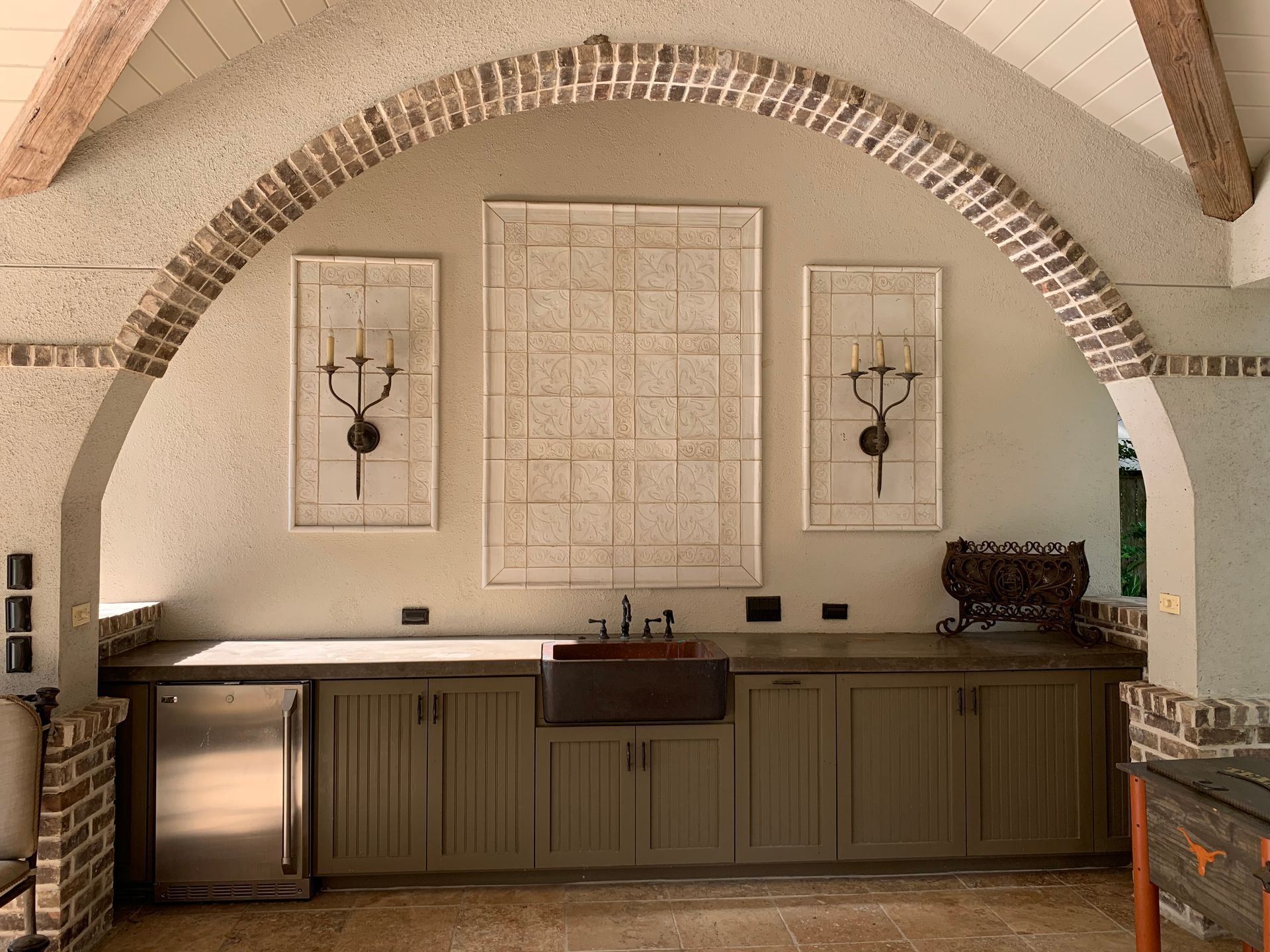 Arched rustic kitchen with stone walls, beige cabinets, and a central window above the counter.