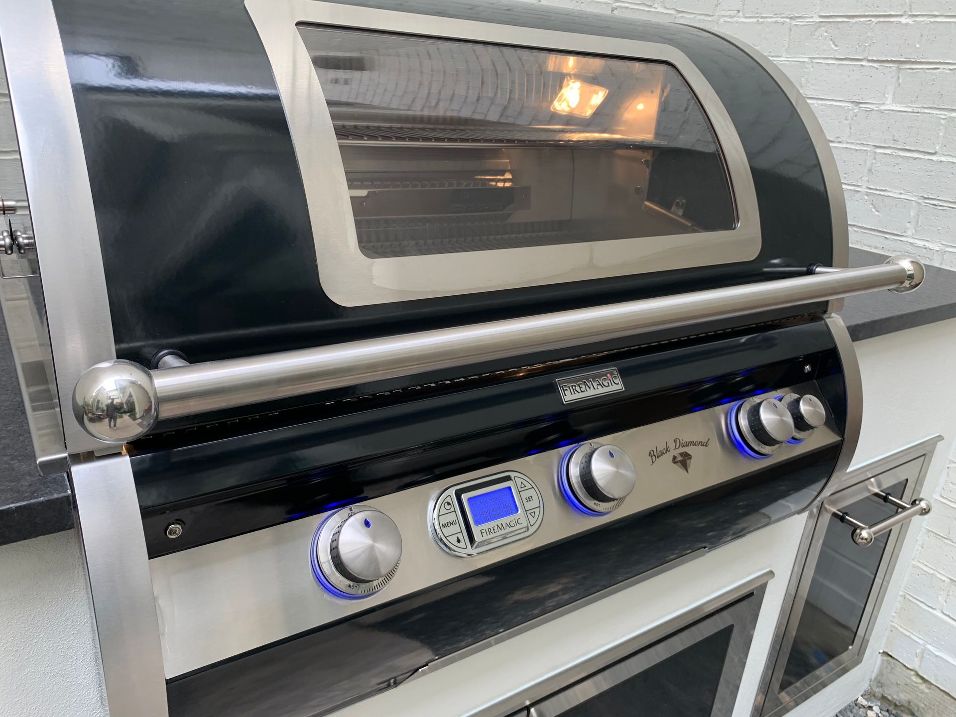 Stainless steel countertop oven with a glass door and blue-lit control knobs in a kitchen setting