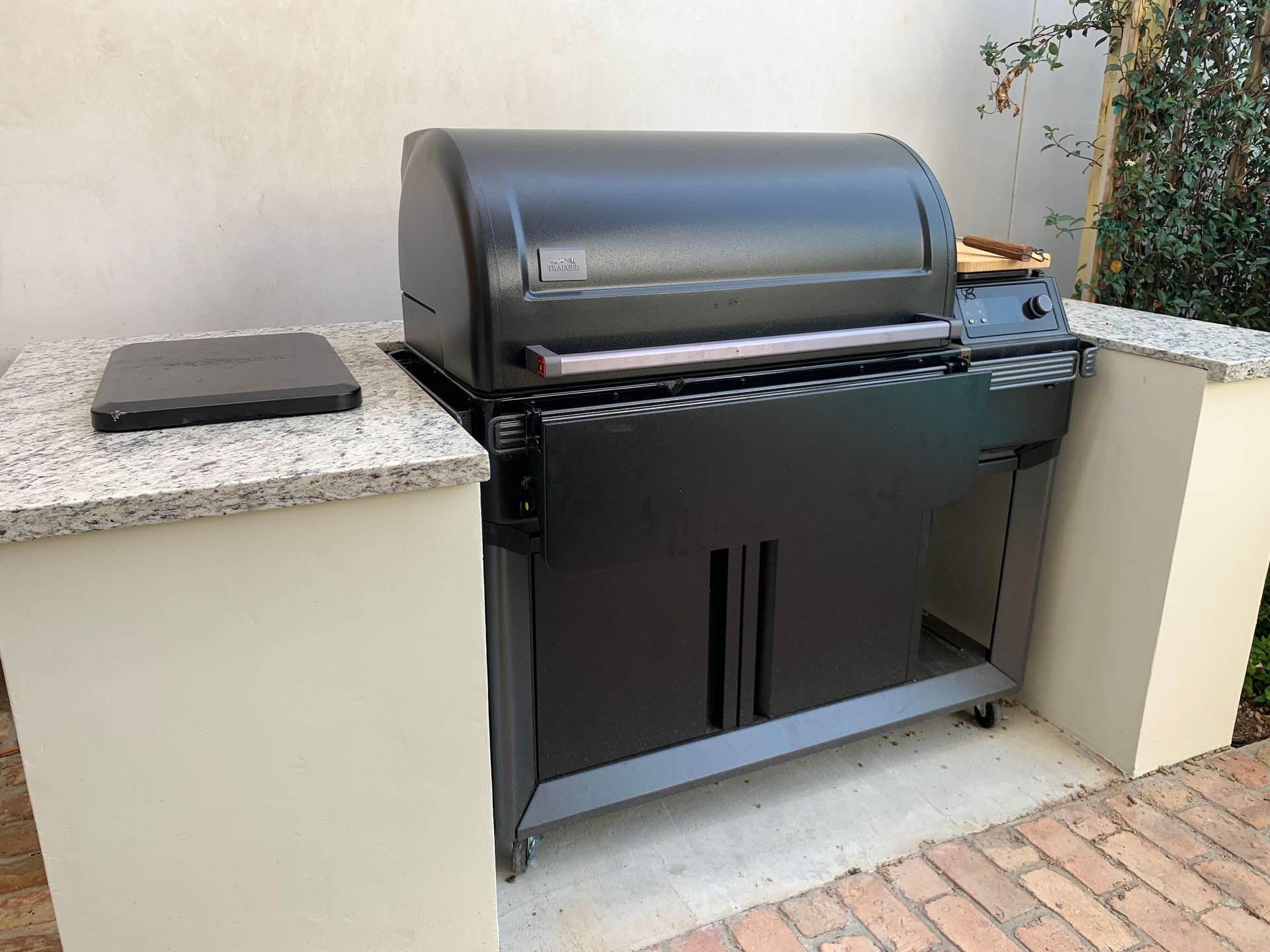 Black outdoor grill built into a stone countertop on a patio.