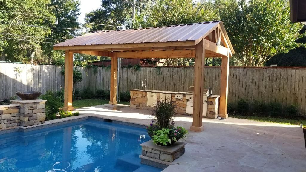 Backyard pool with a wooden gazebo, stone bar, and patio in bright sunlight
