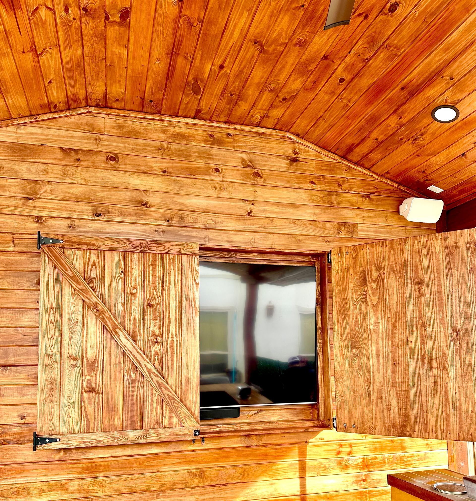 Wood-paneled cabin interior with a wooden loft door and open window under a curved ceiling.