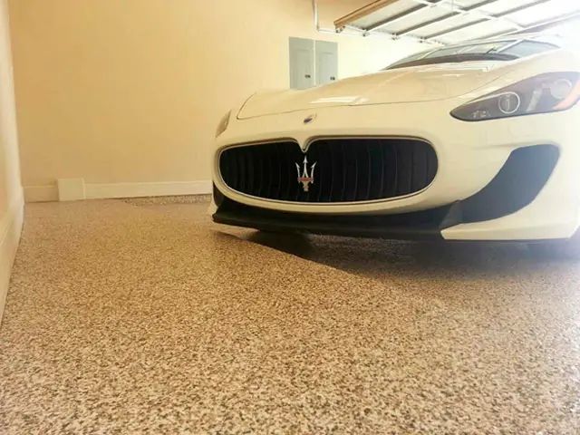 White Maserati parked indoors on a carpeted floor, front view with grille and headlights visible