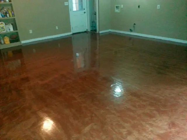Empty room with glossy brown hardwood floor, beige walls, and a doorway in the back.