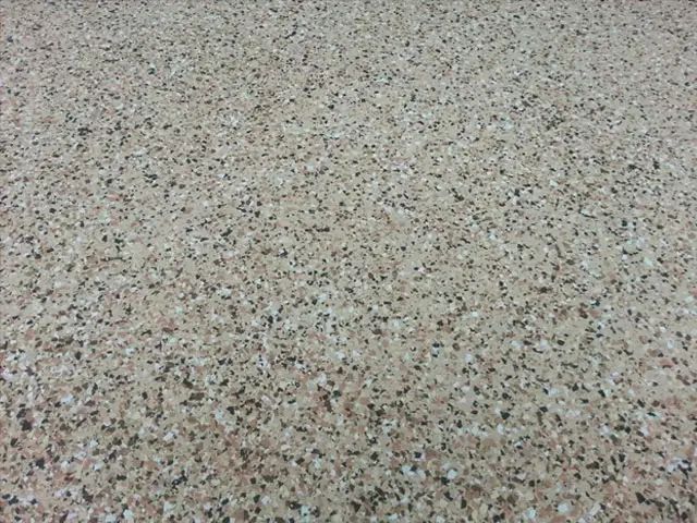 Speckled beige terrazzo floor surface with small black and brown flecks