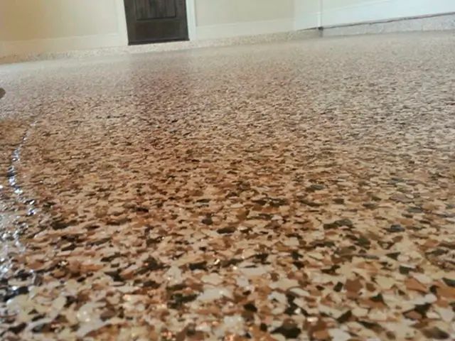 Low-angle view of a speckled terrazzo floor with a doorway in the background.