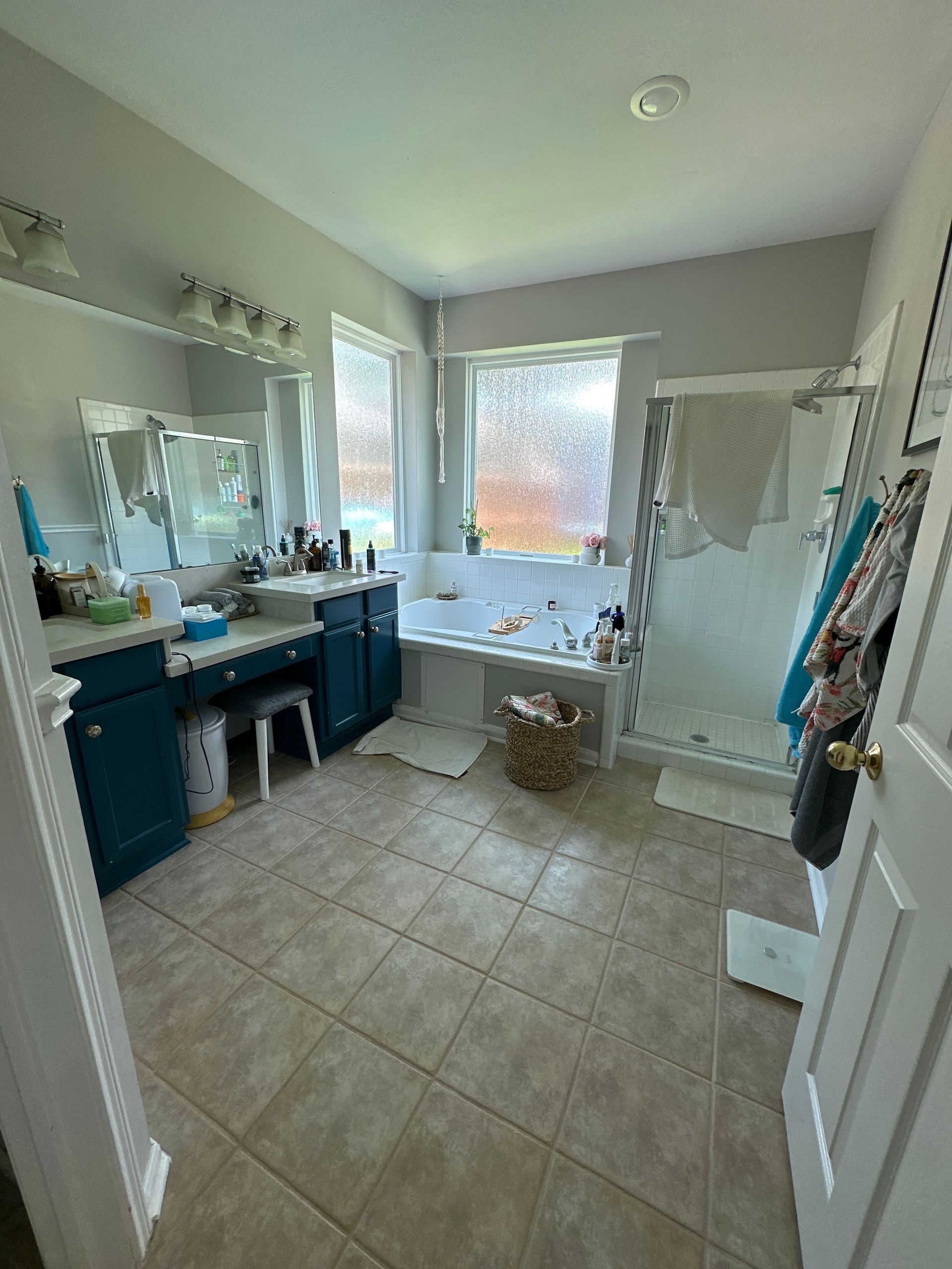 Bathroom with double vanity, large mirror, and a bathtub by a window.