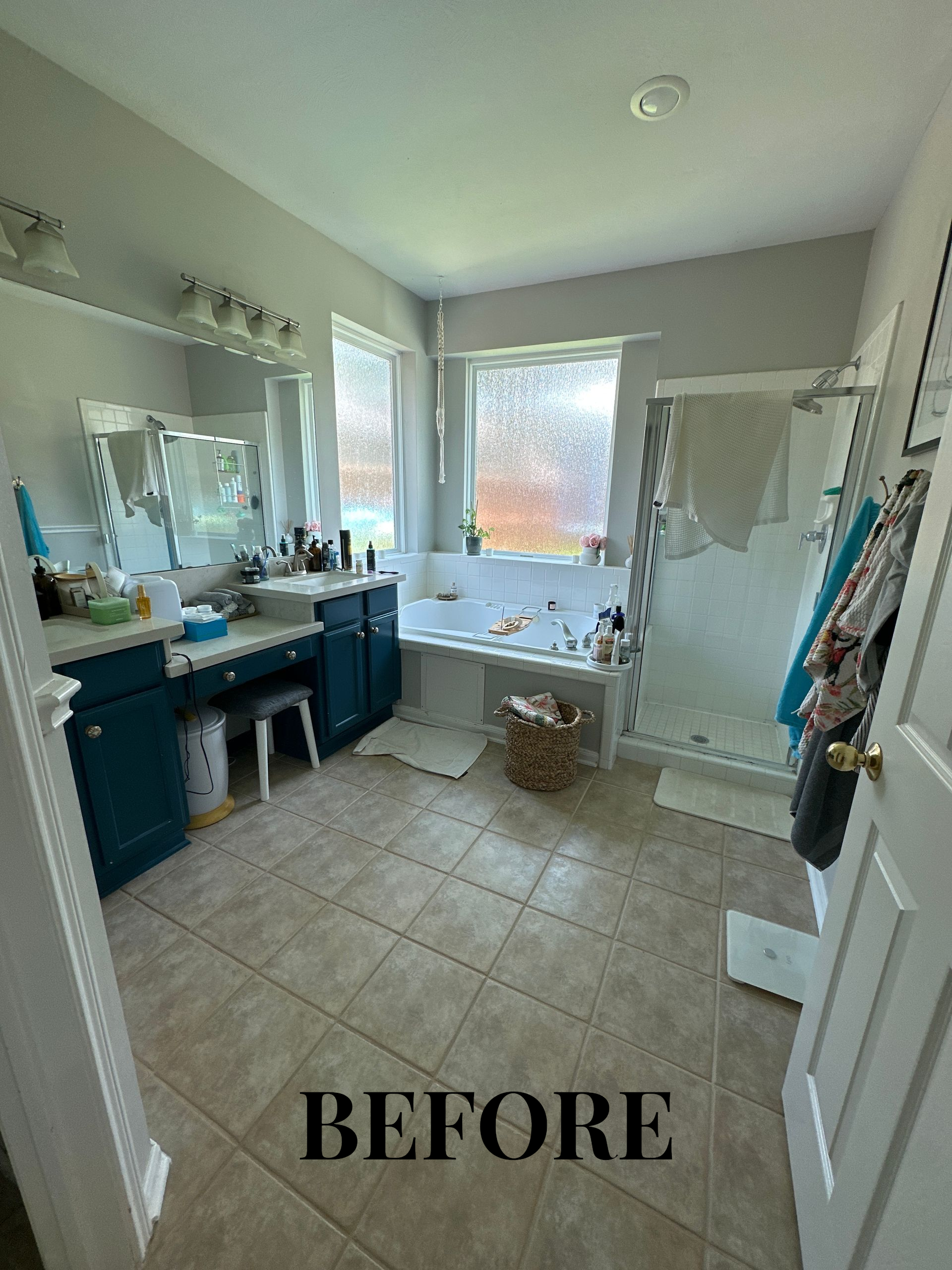 Bathroom interior with double vanity, large mirror, window, and freestanding tub; labeled “BEFORE”
