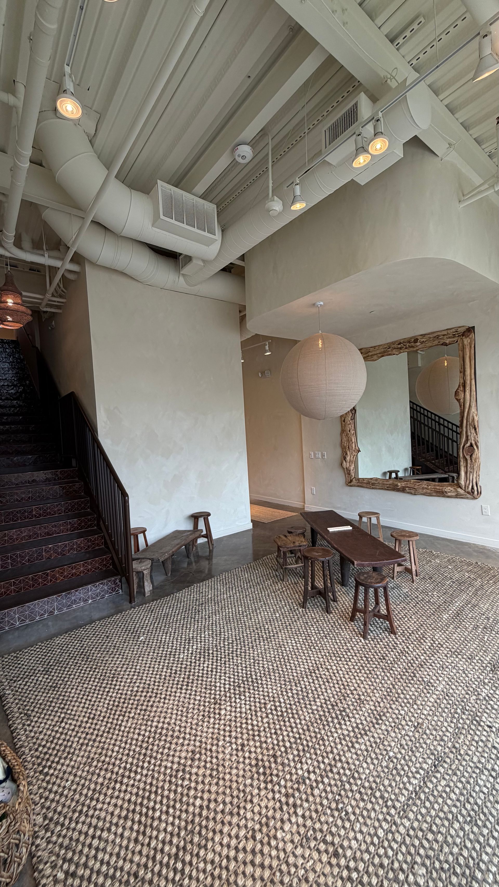 Elegant lobby with patterned carpet, white beams, staircase, and a seating area beside a large mirror