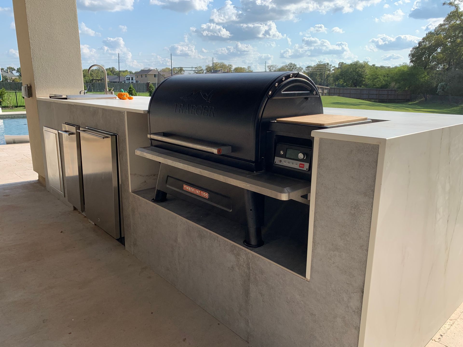 Black grill built into a concrete outdoor counter on a covered patio overlooking a grassy area.