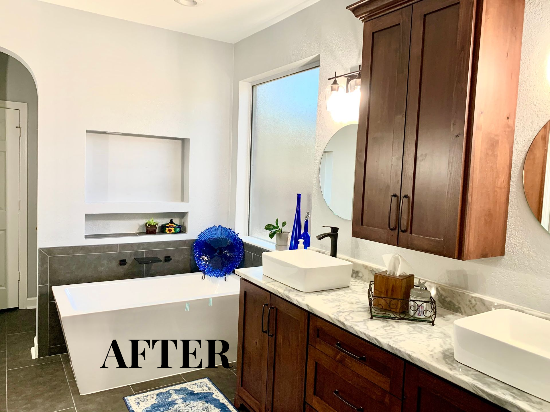 Modern bathroom with dark wood vanity, white countertops, mirror, and a blue flower arrangement, labeled “AFTER”