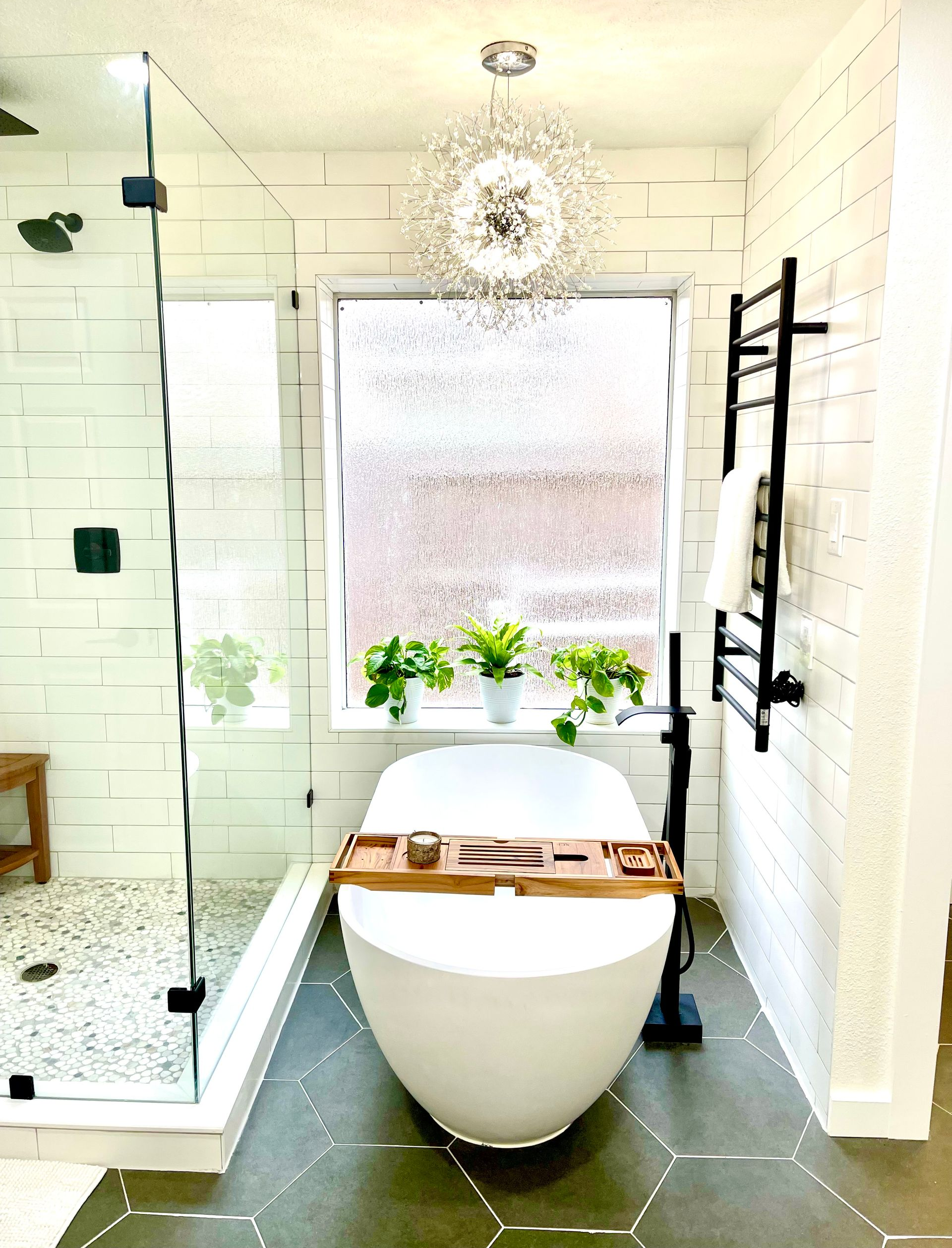 Modern bathroom with a freestanding tub, glass shower, window, and potted plants