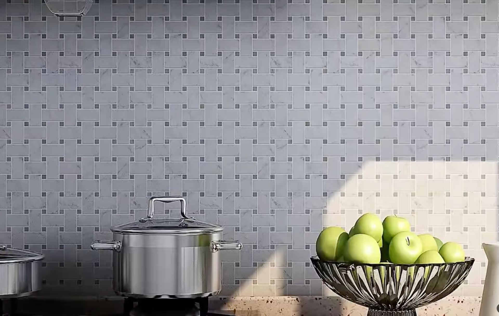 Kitchen counter with stainless pots, tiled backsplash, and a bowl of green apples in sunlight