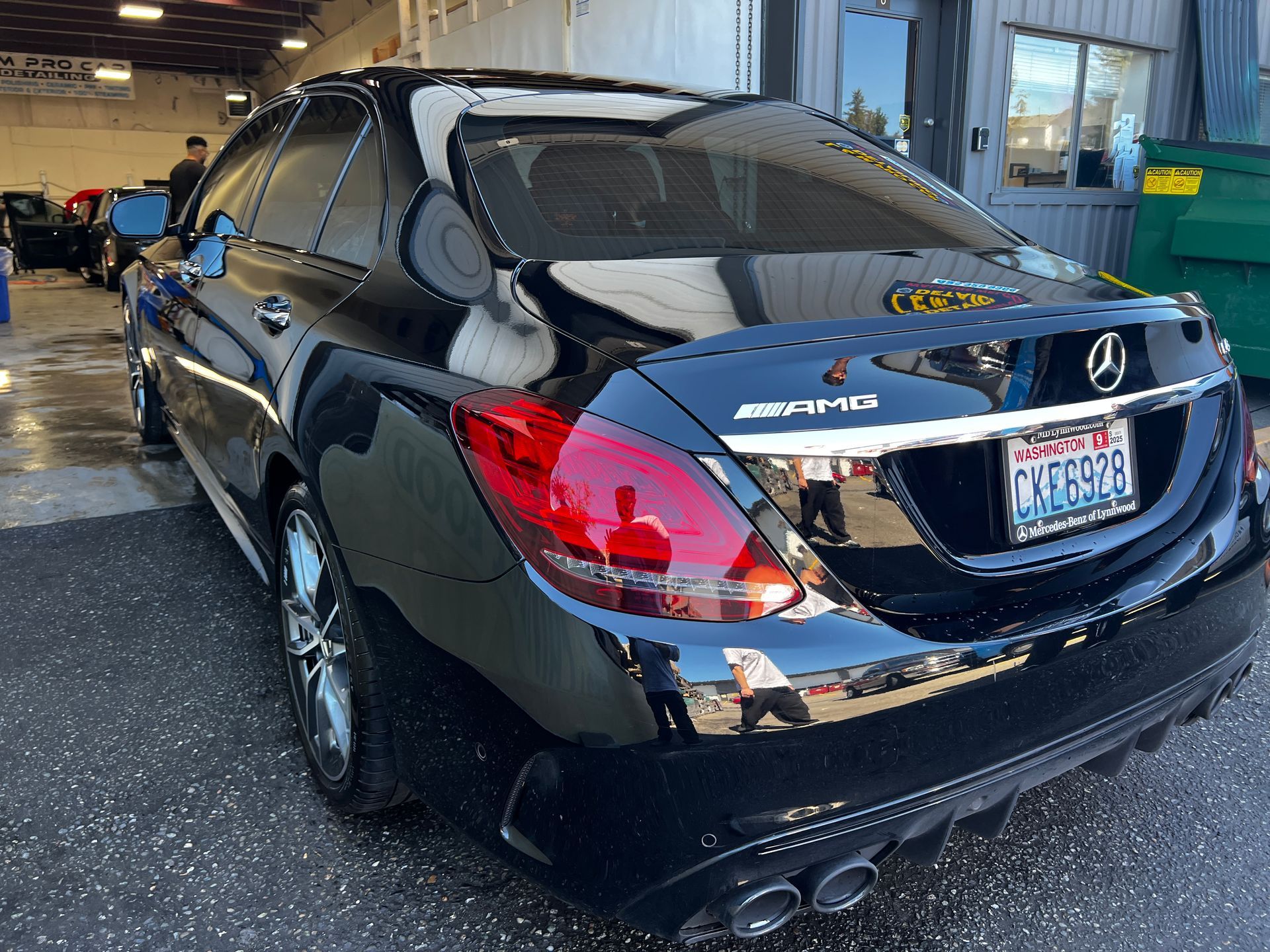 Black Mercedes sedan parked in a garage, rear view with shiny paint and taillights visible