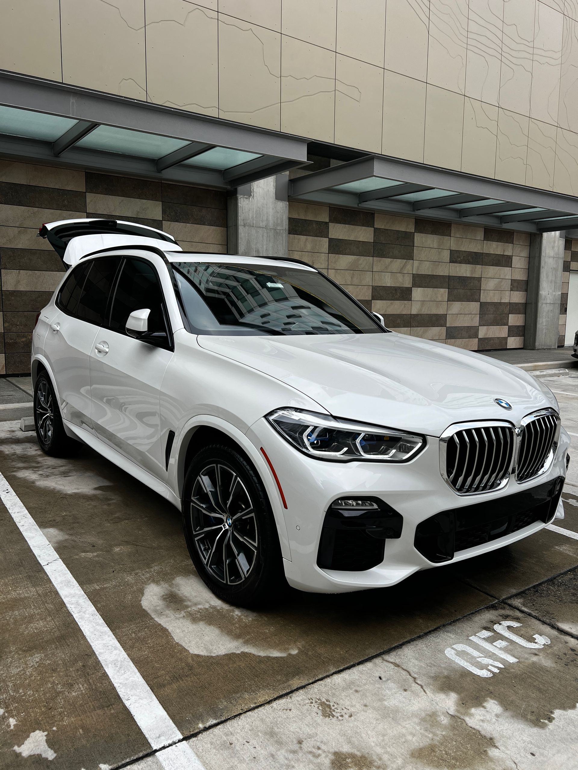 White BMW SUV parked in a covered lot with its rear hatch open