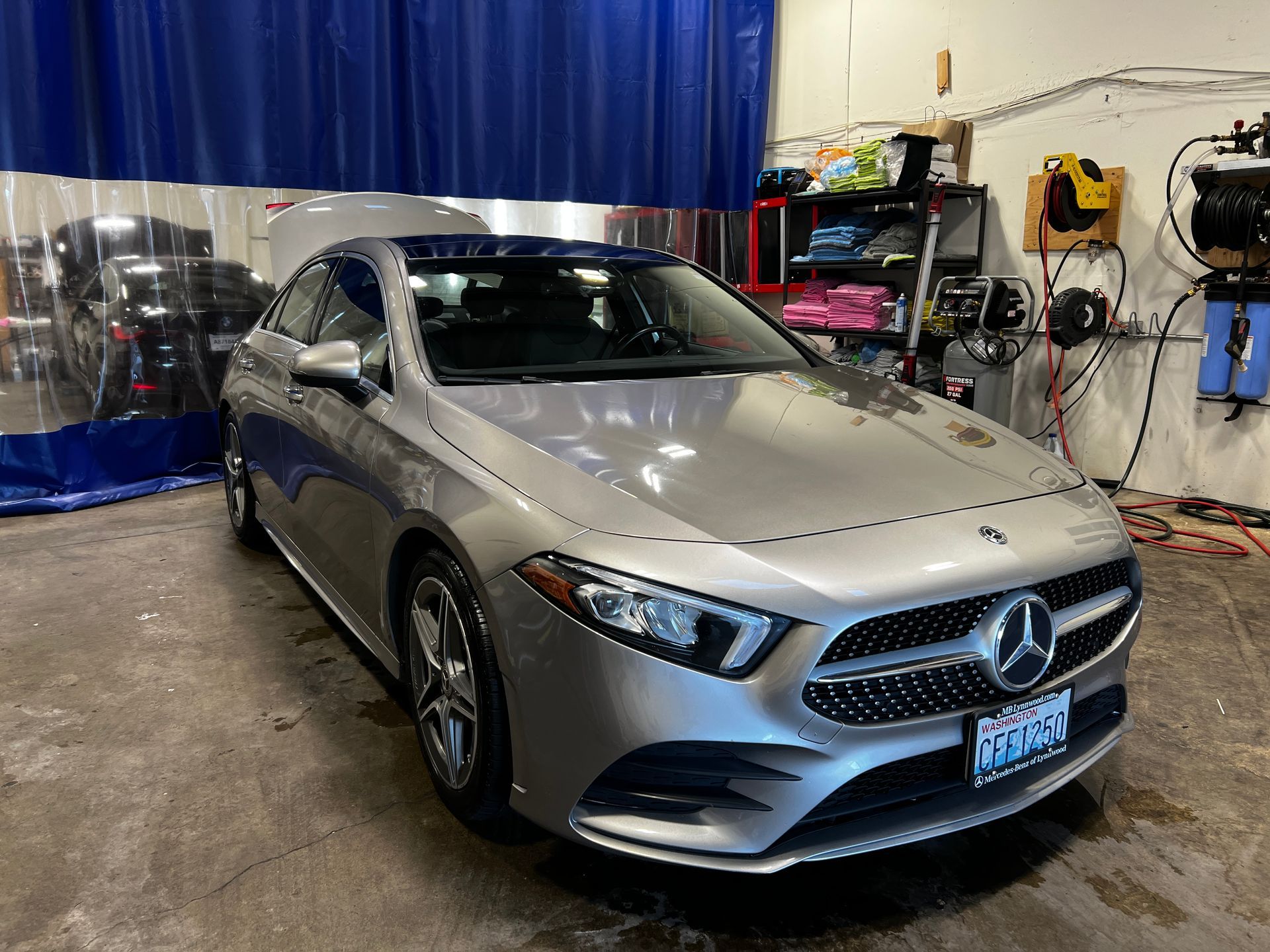 Silver Mercedes sedan parked indoors in a garage, facing slightly left.