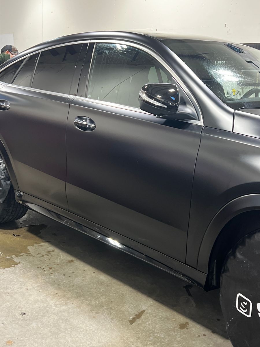 Matte black SUV parked indoors, side view with wet exterior and reflections on the paint