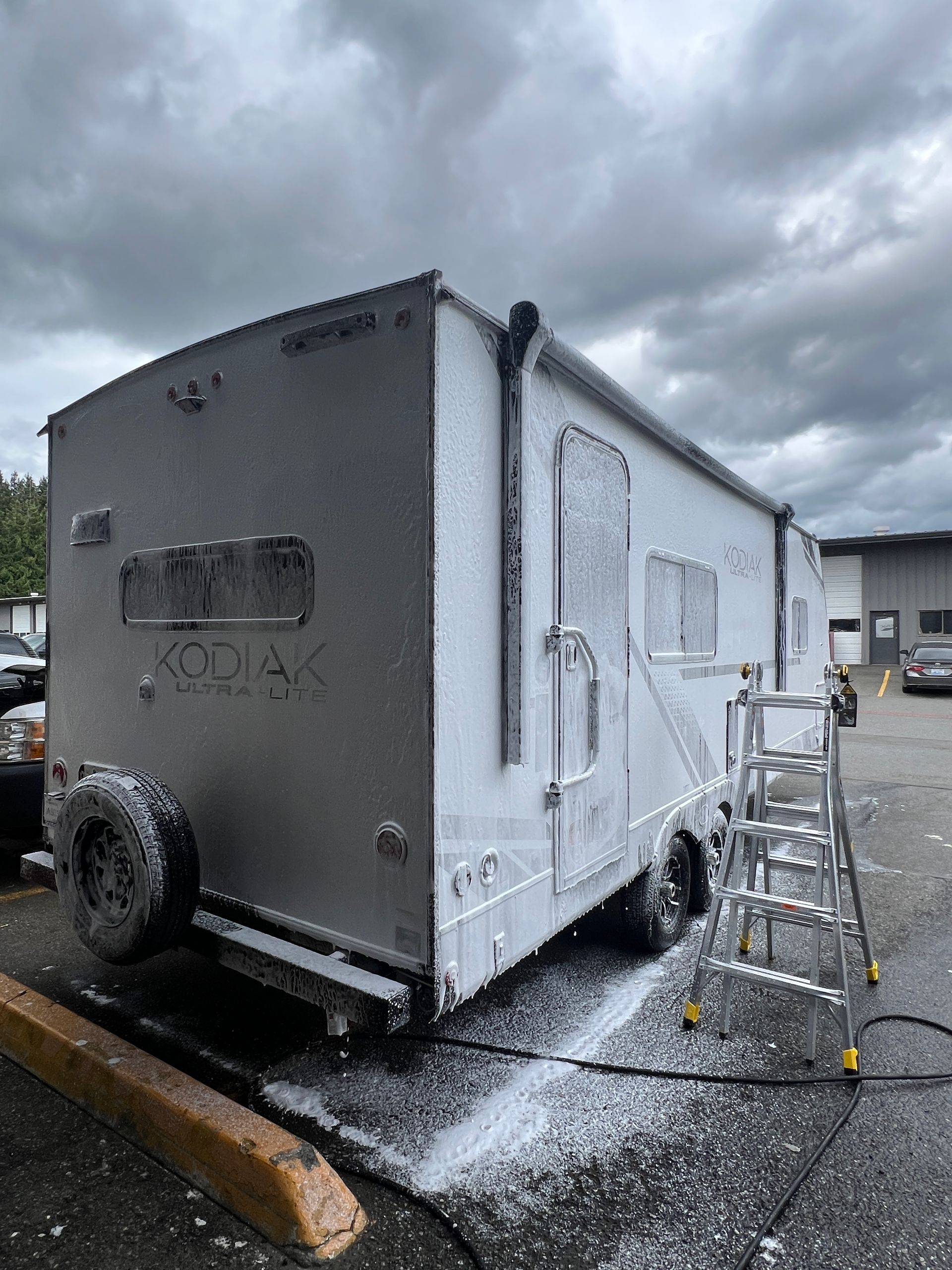 Foam-covered trailer being washed outdoors on a cloudy day