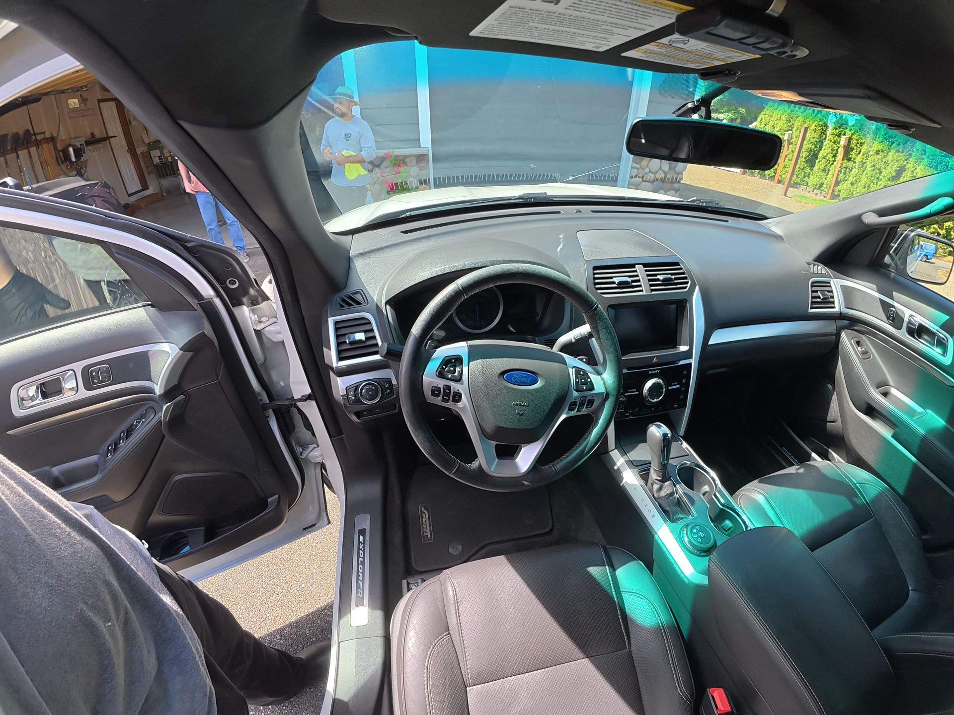 Inside a car interior, showing the steering wheel, dashboard, and open driver's door in daylight.