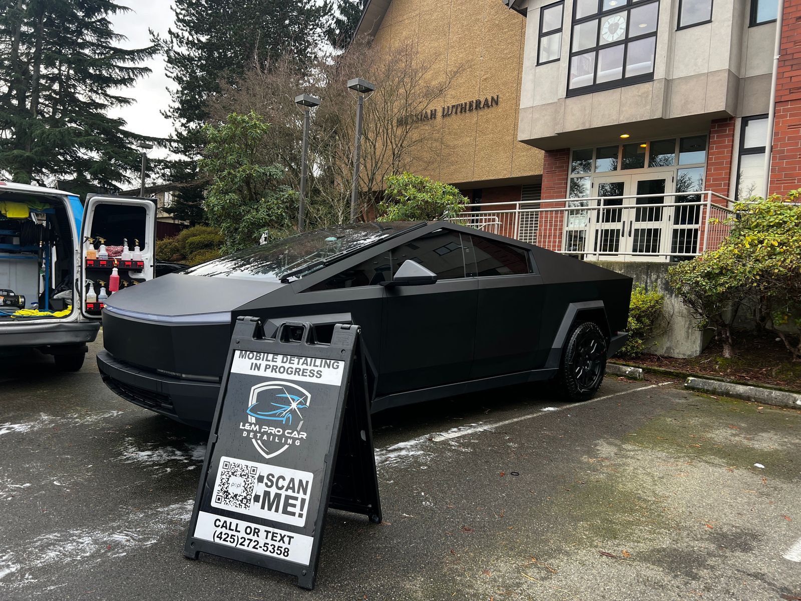 Black pickup truck parked outside a building with a sidewalk sign in front