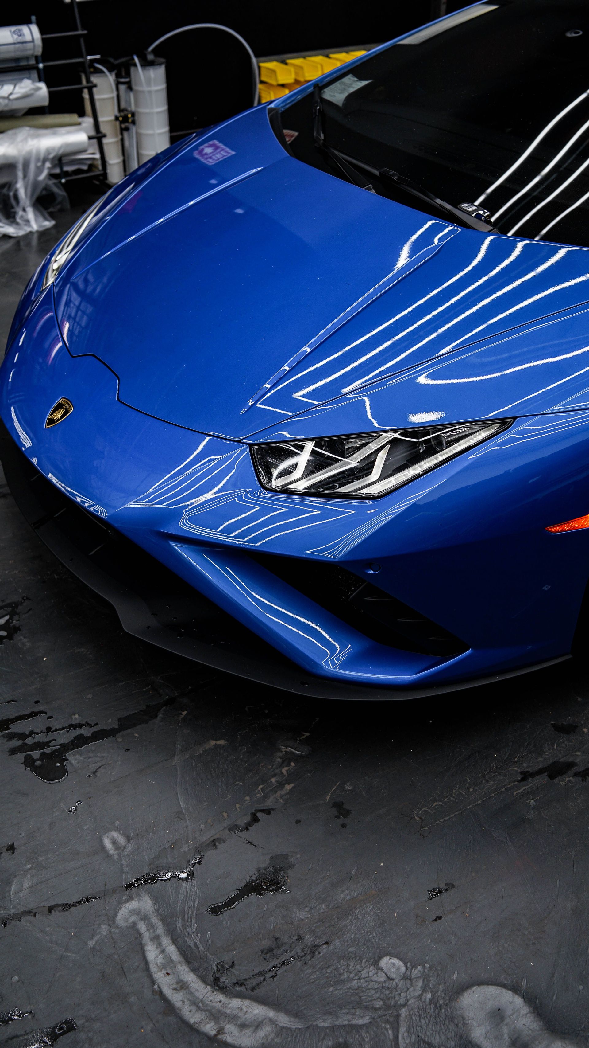 Blue sports car in a wet garage, front view with headlights and reflections on the hood