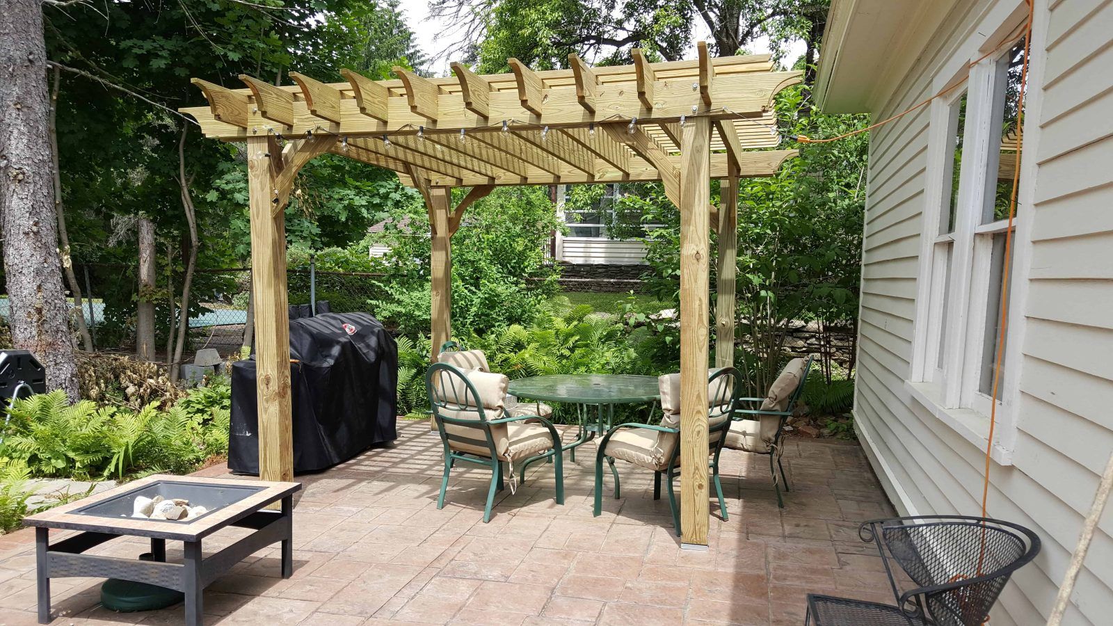 A black house with a wooden deck and a pergola.