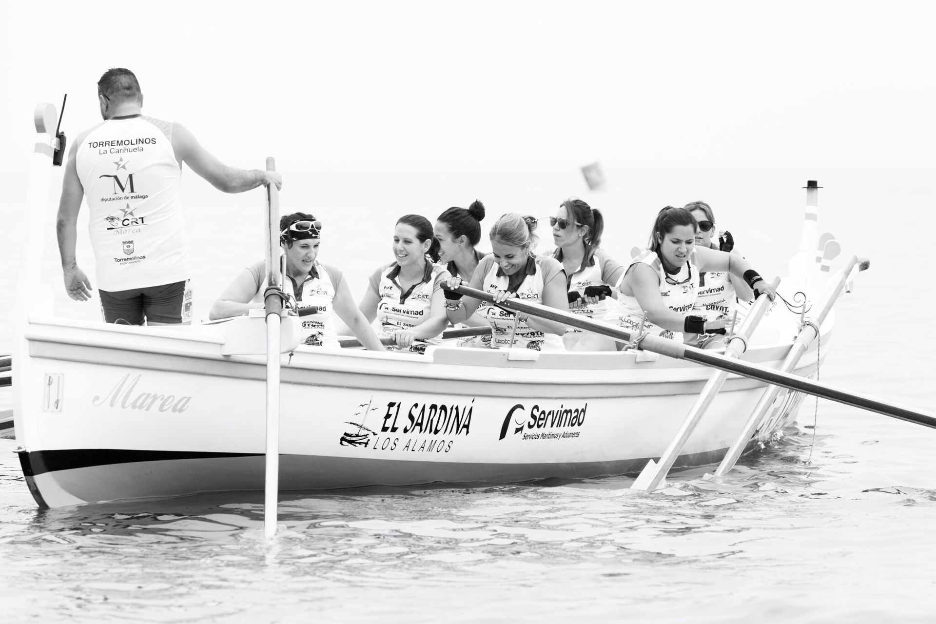 A group of people are rowing a boat in the water.