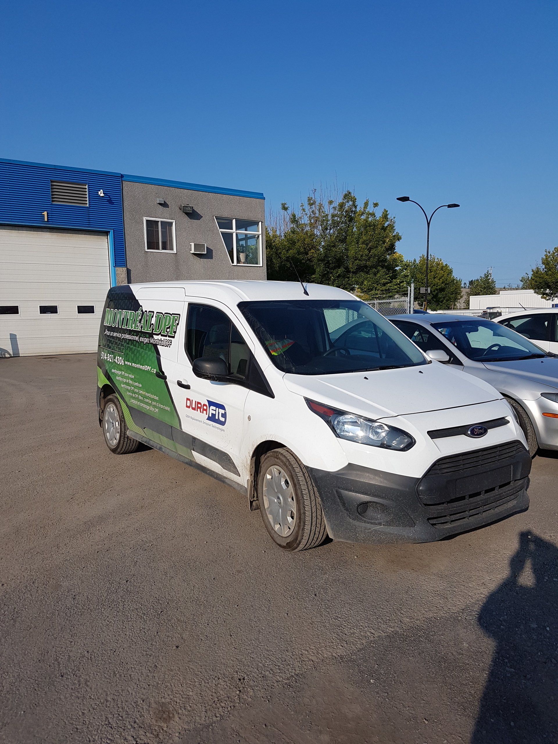 Une camionnette blanche est garée devant un immeuble.