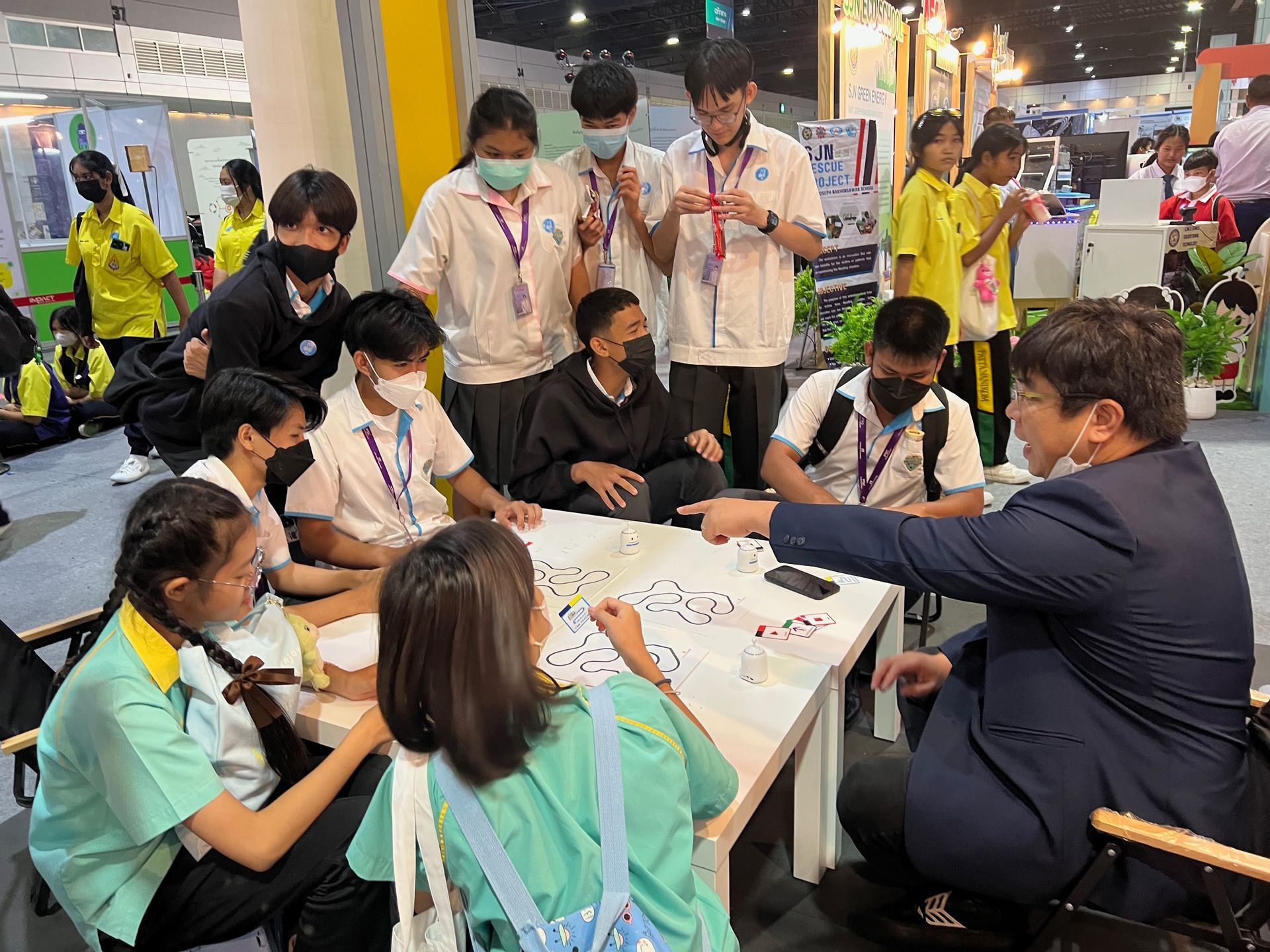 A group of people are sitting around a table with a man in a suit.