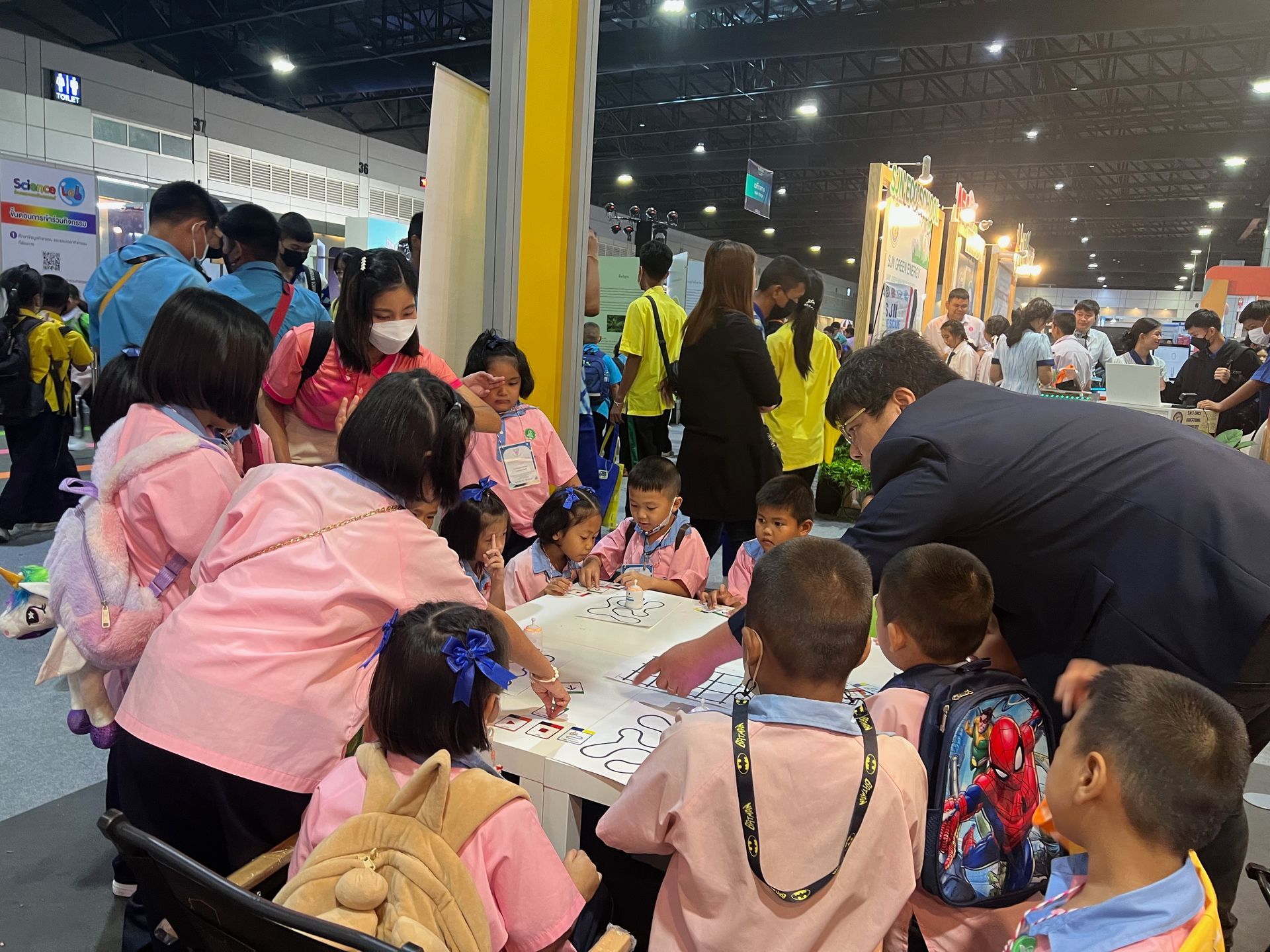 A group of children are sitting around a table at a convention.