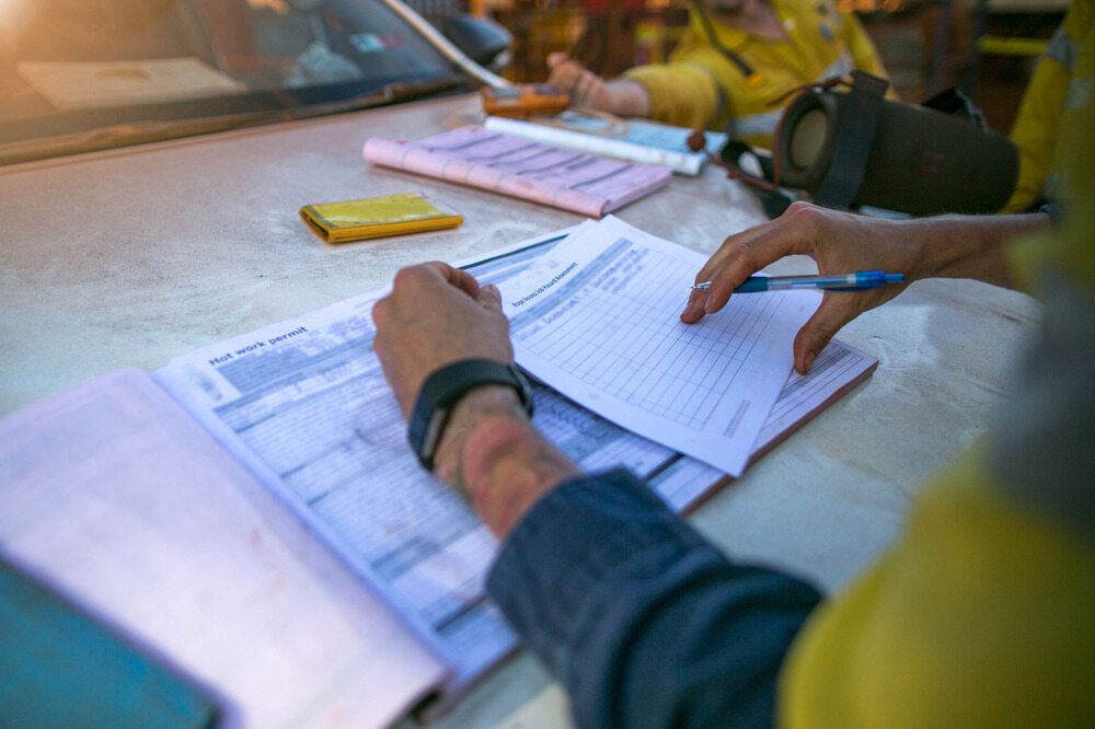 A Person is Sitting at a Table Writing on a Piece of Paper — Advanced Industry Training In South Townsville, QLD