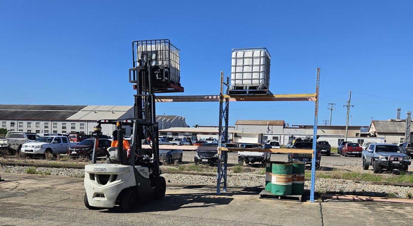 A Forklift is Loading a Pallet of Containers on a Rack in a Parking Lot — Advanced Industry Training In South Townsville, QLD