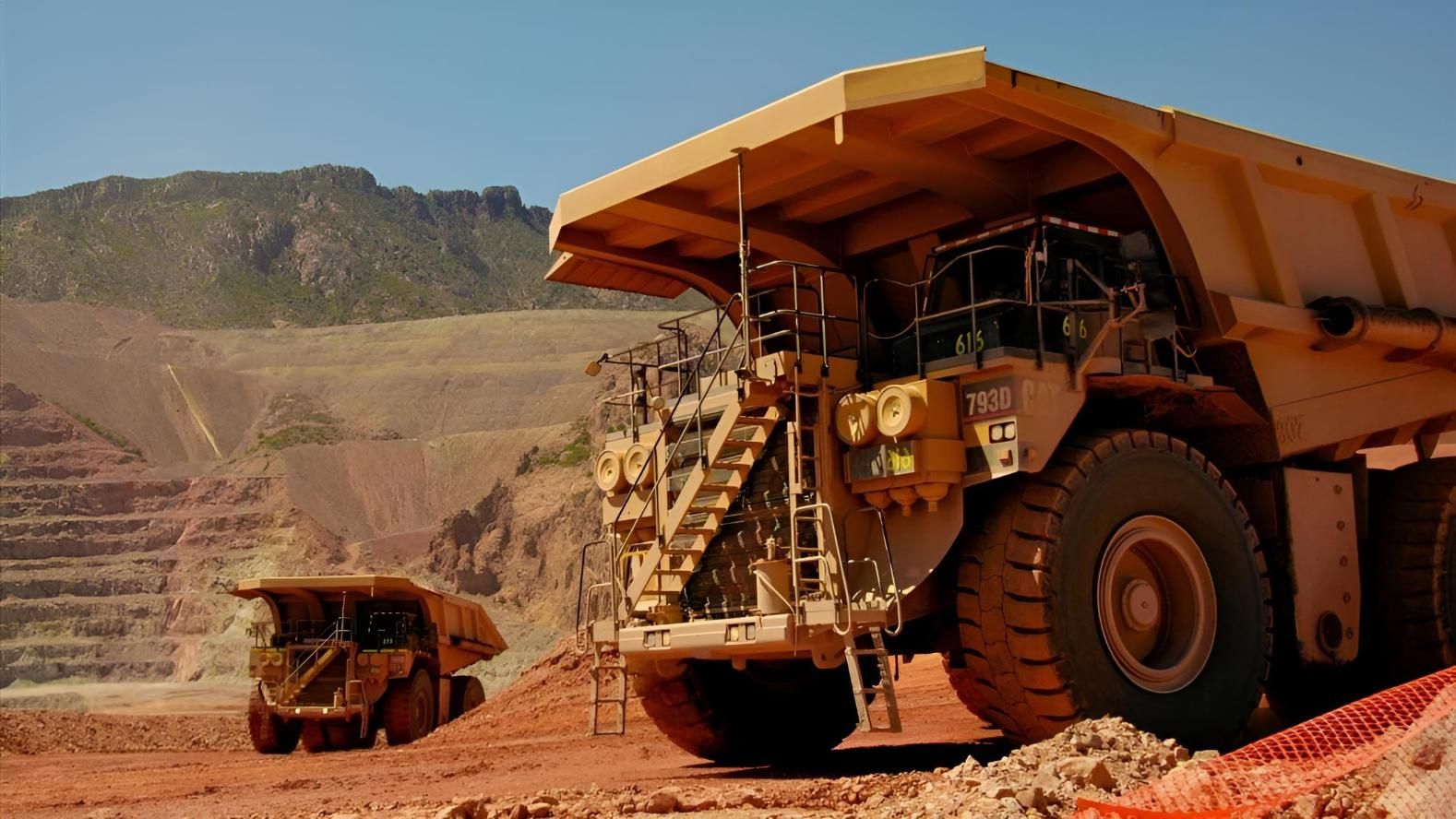 Two Large Dump Trucks Are Parked in a Dirt Field — Advanced Industry Training In South Townsville, QLD