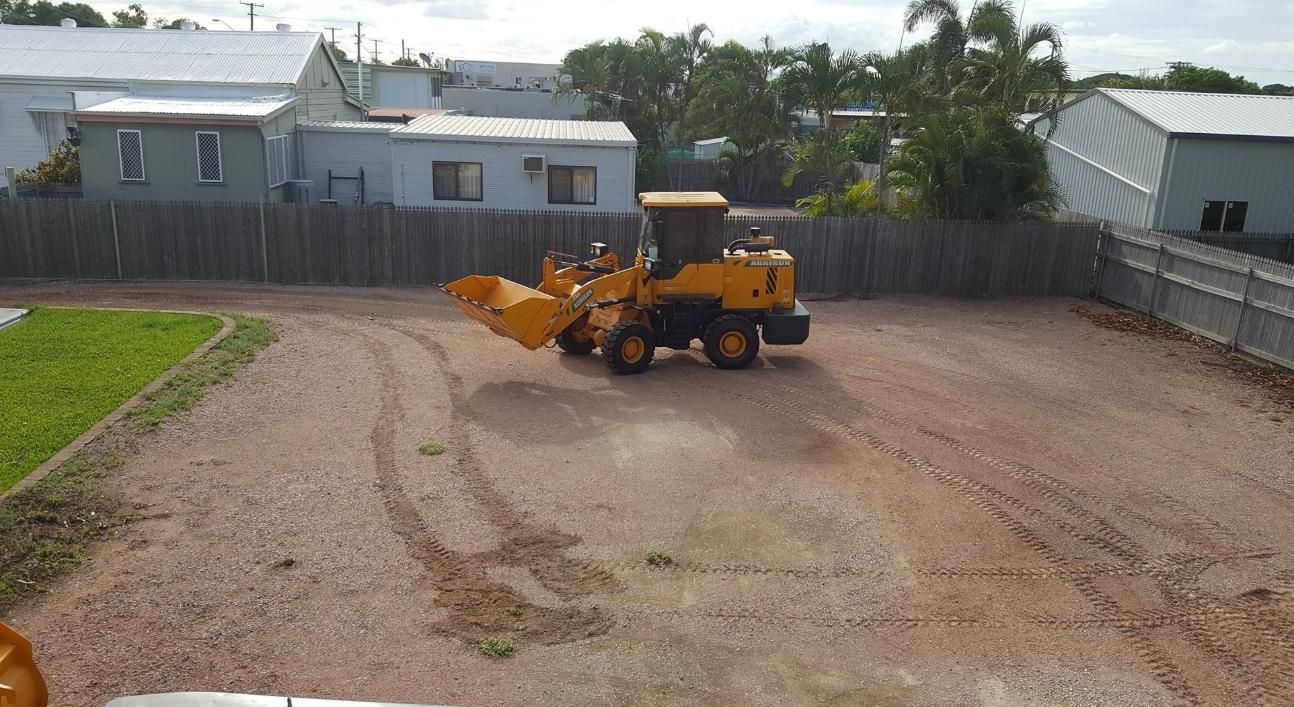 A Yellow Bulldozer is Driving Down a Dirt Road — Advanced Industry Training In Cairns, QLD