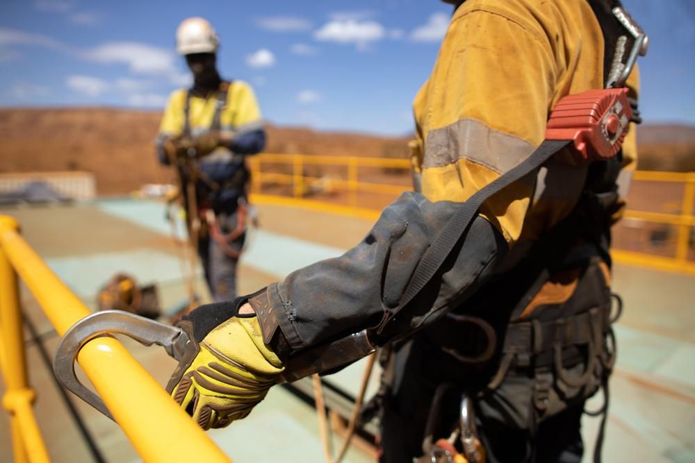 A Man Wearing a Safety Harness is Holding Onto a Railing — Advanced Industry Training In South Townsville, QLD