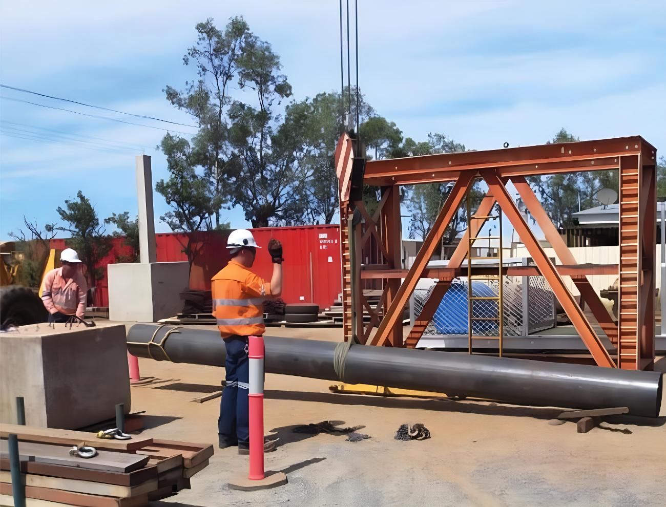 A Man Wearing a Hard Hat is Standing Next to a Large Pipe — Advanced Industry Training In South Townsville, QLD