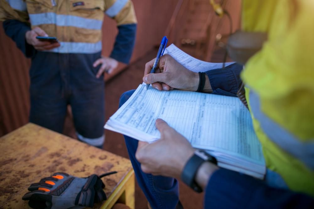 A Man is Sitting at a Table Writing on a Piece of Paper — Advanced Industry Training In Mackay, QLD
