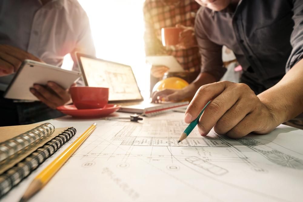 A Group of People Are Sitting at a Table Looking at a Blueprint — Advanced Industry Training In Rockhampton, QLD