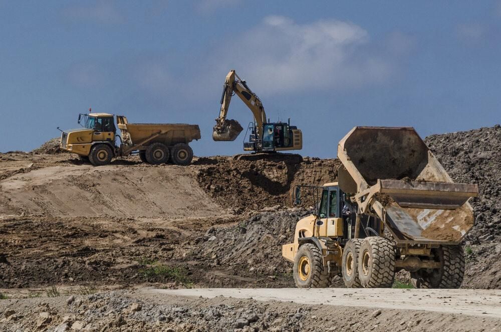 A Dump Truck is Being Loaded With Dirt by an Excavator — Advanced Industry Training In Rockhampton, QLD
