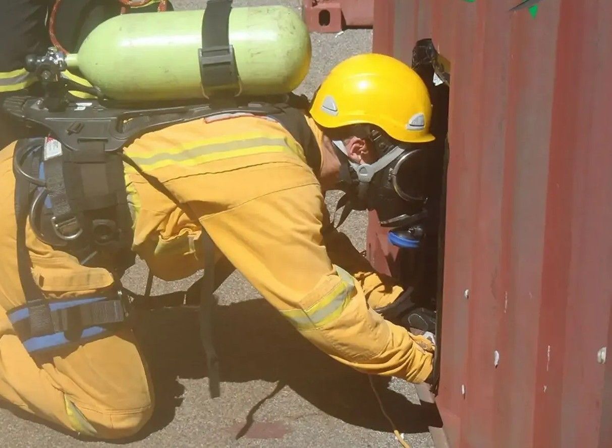 A Fireman is Kneeling Down and Looking Through a Hole in a Wall — Advanced Industry Training In South Townsville, QLD